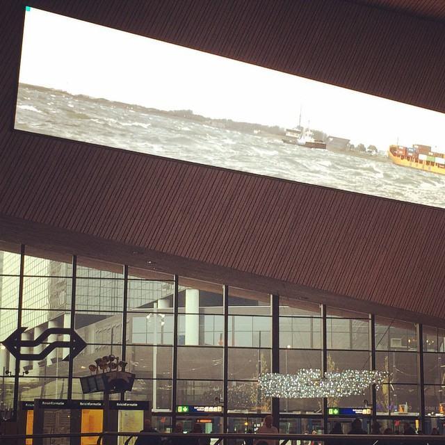 Beeld Rotterdamse haven op scherm in hal Rotterdam Centraal